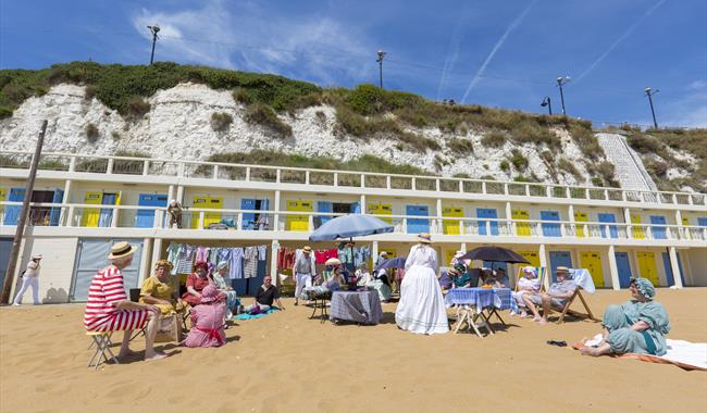 People dressed in Dickensian costume sat on beach