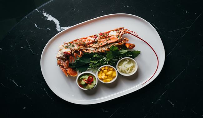 A plate of lobster with fresh mango salsa on a bed of greens.