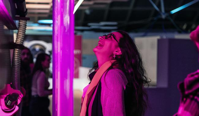 woman playing on an exhibit illuminated pink from the disco lights