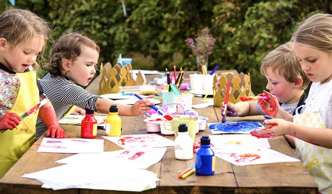 Children sat at a table outdoors doing crafts