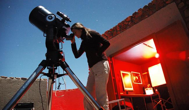 woman looking through telescope at the night sky