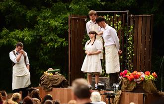 Two boys and one girl standing in front of a boy with his head in his hands