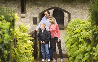 A family standing on the drawbrige outside Ightham Mote