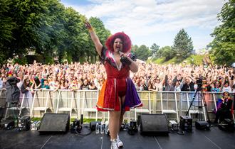 Photo of Delilah Tickles in front of the crowds at the Pride Canterbury main stage.