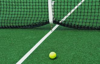 Yellow ball on green tennis court