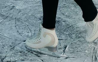 Person in white figure skates on fresh ice