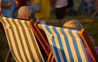 Two people sat in a deckchair at a summer event