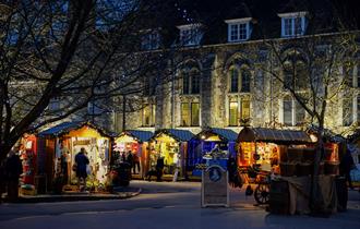 Winchester Cathedral Christmas Market chalets, with Winchester Cathedral in the background at night.