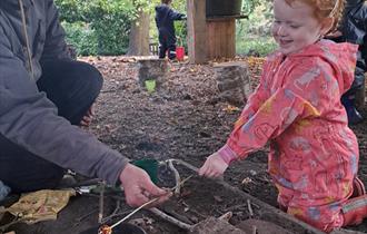 Child at campfire toasting marshmallows at Painshill