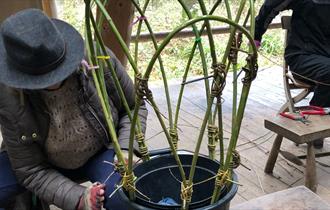 A woman making a plant support