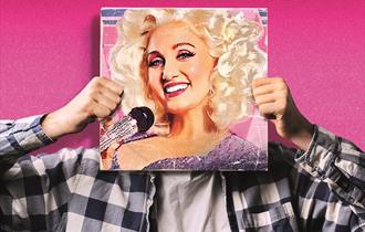 Against a bright pink sparkly background, someone holds a record in front of their face. The record cover shows a painting of Dolly Parton with bright