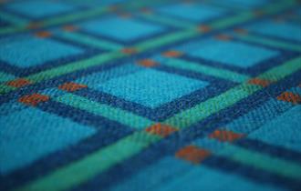 image of one of the fabrics in the exhibition which is blue, green and red design woven in wool