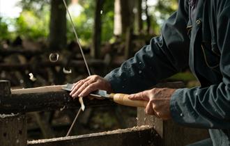 craftsman using chisel on turning piece of wooden leg