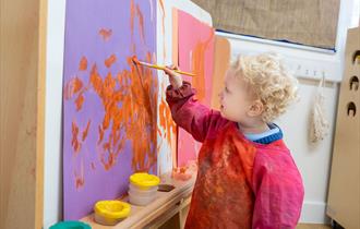 Nursery age child taking part in a painting activity