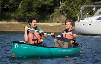 Two people splashing about on the water on a canoe.