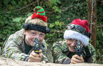Two people in Christmas headbands, holding BattleZone guns