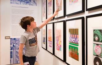 Child pointing at framed artwork on gallery wall