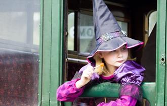 Girl dressed up as a witch looking out of the carriage window at the Wizard Week event, Isle of Wight Steam Railway, what's on