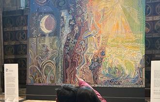 2 children looking at a large tapestry