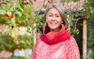 A woman stands in front of trees with fruit growing