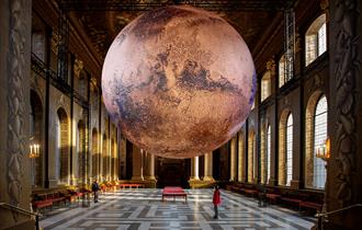 A large, realistic rendering of the planet Mars is suspended in the center of the Painted Hall. The Mars exhibit is spherical and measures seven meter