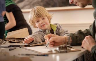 Young child and Adult at a table with art supplies drawing on a paper