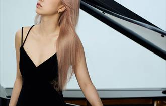 Pianist Fangwei Zhao in front of a grand piano