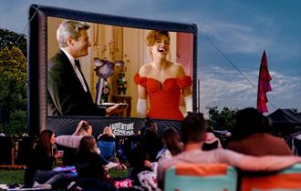 Visitors enjoy outdoor cinema seated on camping chairs.