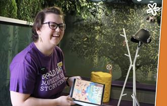 Woman in a purple t-shirt smiling and holding a book