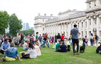 Groups of people hanging out in the lawns of the Old Royal Naval College, next to the Thames