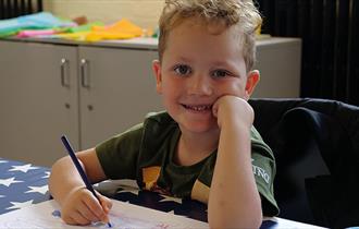 A child smiles at the camera enjoying the family activities at Bletchley Park