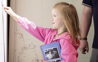 A girl enjoying playing with an interactive screen in an exhibition at Bletchley Park