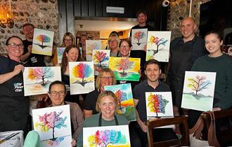 Painting party group holding finished paintings on canvases