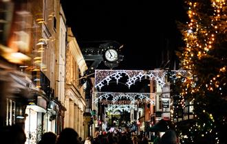 Winchester high street at night with Christmas lights and a Christmas tree.