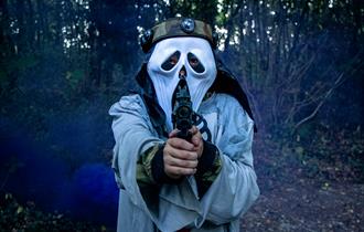 A person in a halloween mask, holding a laser tag gun