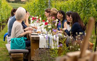 People sat around a table in the vineyard eating