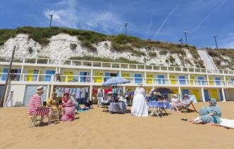 People dressed in Dickensian costume sat on beach