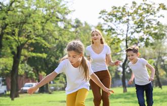 Two children and an adult playing an outdoors game