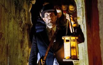 Man with a lantern exploring Carisbrooke Castle in the dark, Halloween event, what's on, Isle of Wight