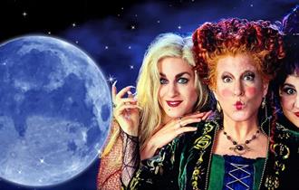 Hocus Pocus movie poster. A dark, starry background with a full moon on the left and 3 witches on the right.