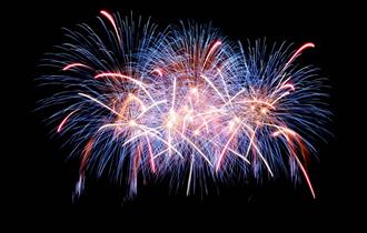 Stock photograph of fireworks going off against a black night sky