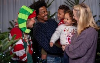 Family laughing surrounded by Christmas trees