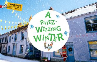 A photograph of the outside of the Roald Dahl Museum during a snow storm, with Mother Christmas carrying presents