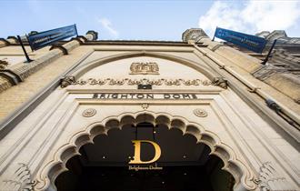 The exterior main entrance of Brighton Dome, the shot is taken looking up toward the Dome sign above an intricate doorway.