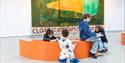 Children drawing and creating artwork in a Hastings Contemporary gallery beside a large colourful painting.