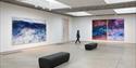 Visitor viewing large abstract paintings in a bright gallery space at Hastings Contemporary.