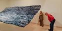 sitors exploring a large wave-inspired art installation at Hastings Contemporary.