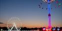 Big wheel ride and the high swing ride with the sun set in the background at the Isle of Wight Festival, music event, what's on