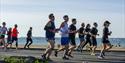 Runners doing the Great South Run with the sea behind