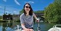 Lady steering a boat on the river with blue skies - Cotswold Boat Hire